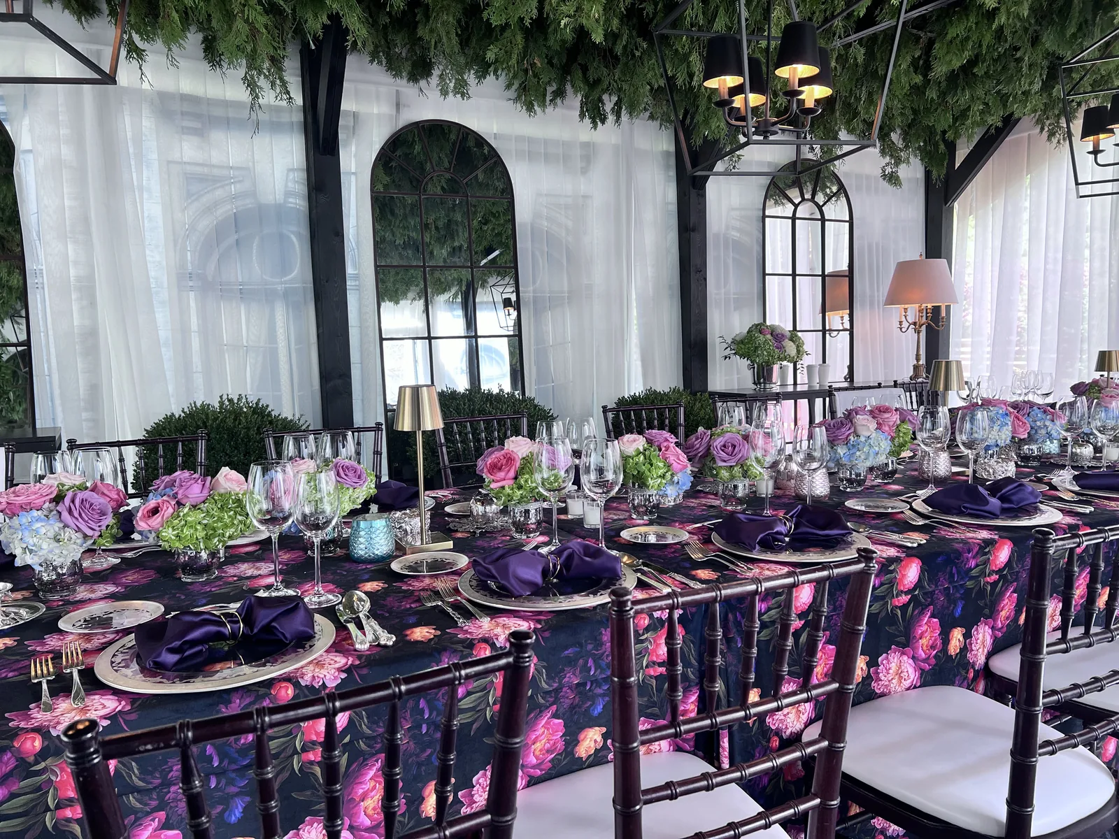 Custom dark floral table linen across a dining table with purple napkins and fresh flowers