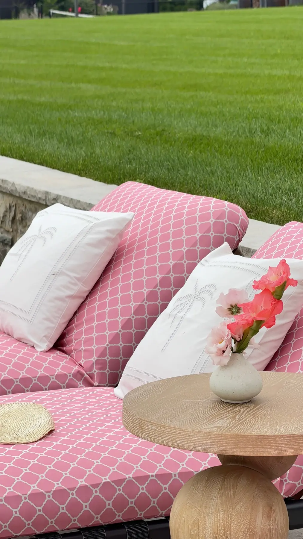 Close-up of pink geometric printed upholstery with white cushions and a wooden side table